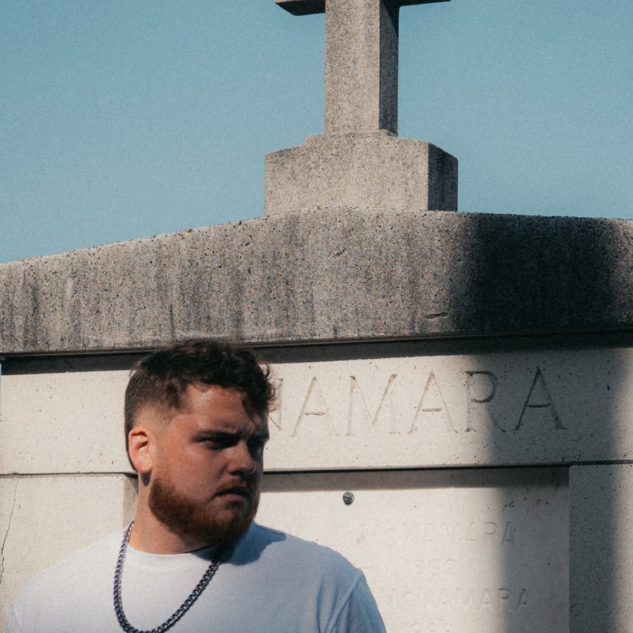 Tanner Castille in front of a stone tomb topped with a cross